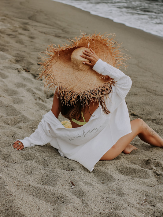 Women sitting on beach wearing straw hat and Maid Bridal Wifey Linen Shirt Cover Up for Honeymoon and Newlyweds